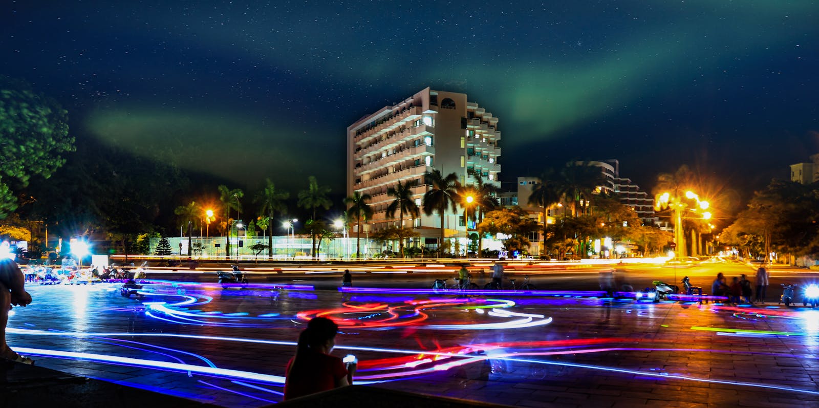 Captivating cityscape of Đắk Ya, Vietnam at night with vibrant light trails and an illuminated building.