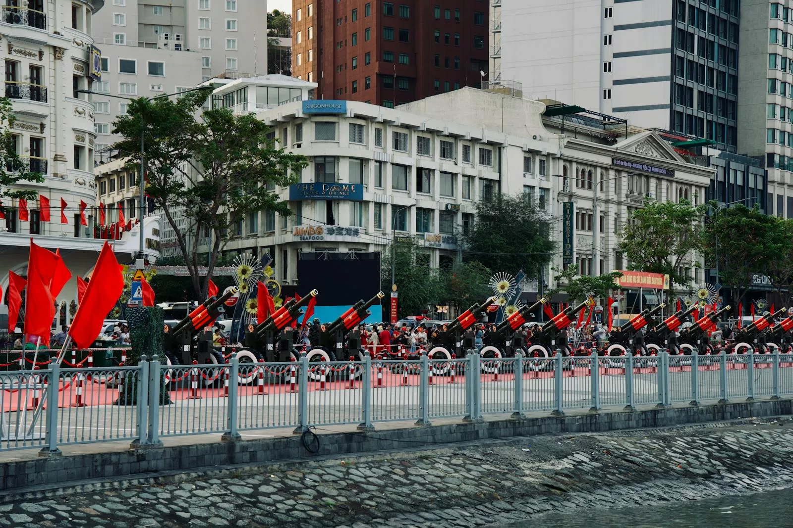 A vibrant parade with red flags set in an urban cityscape, featuring bustling streets and modern architecture.